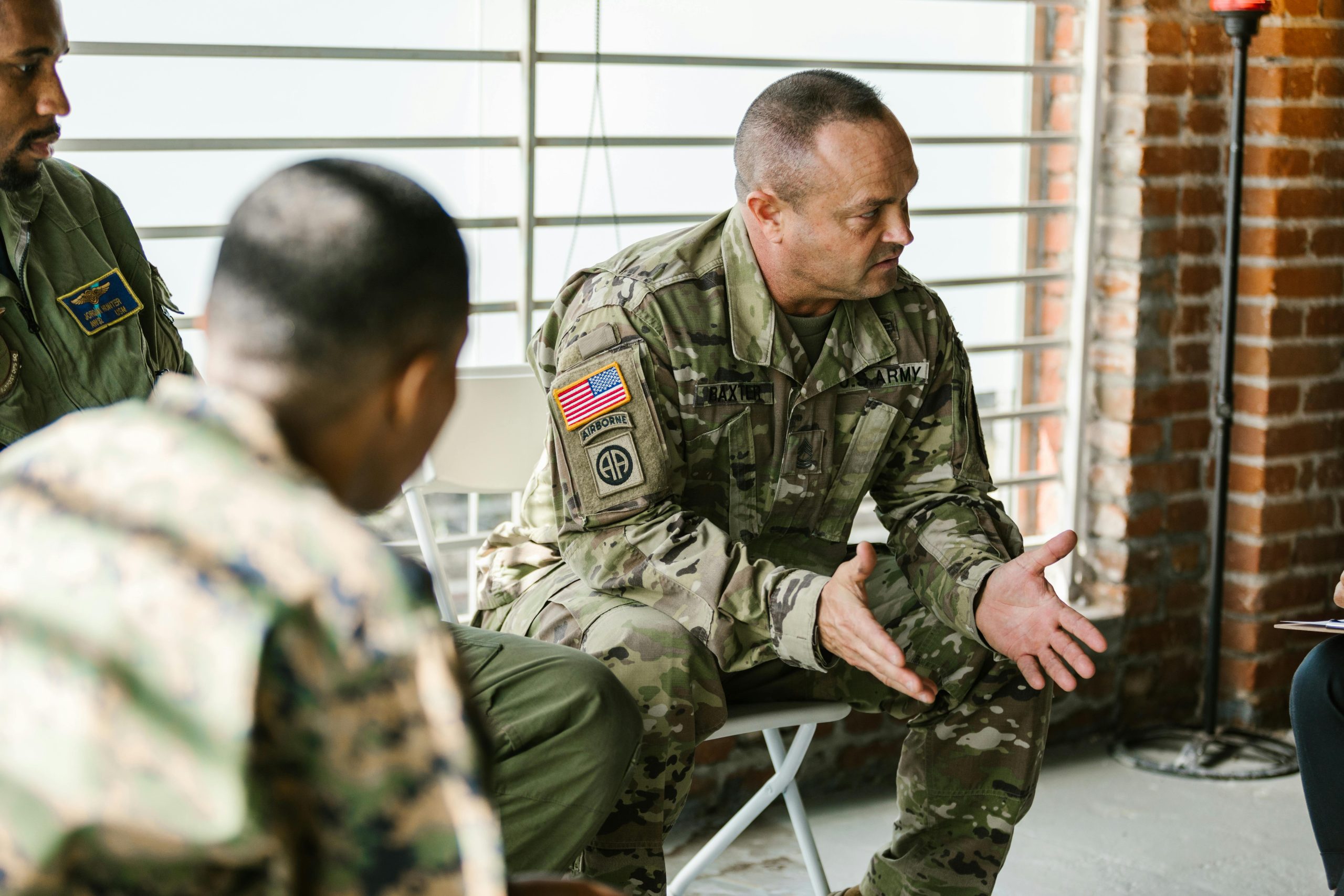 A veteran in uniform talks with two fellow service members in a peer support conversation